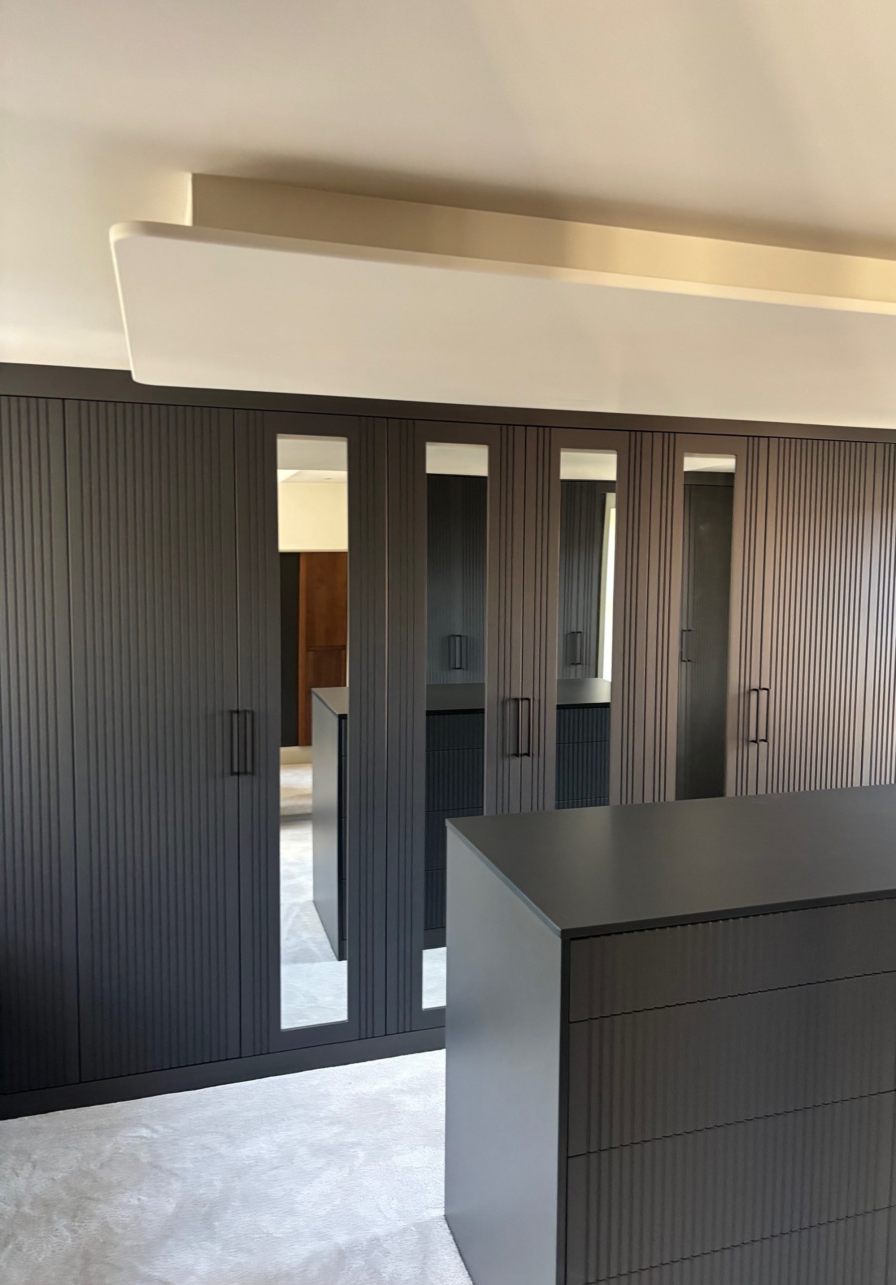 Graphite hinged wardrobes with mirror-glazed doors and dressing island