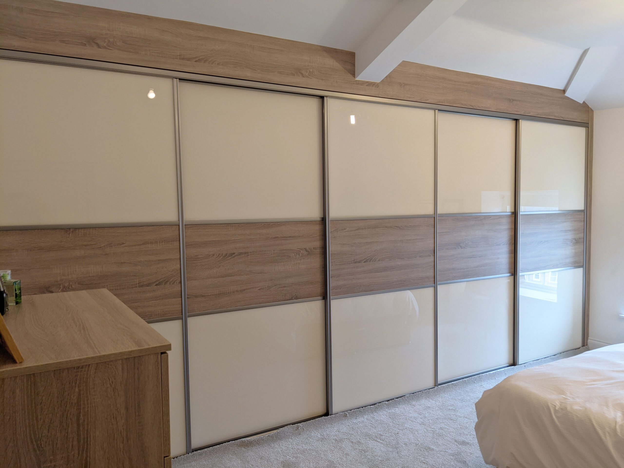 Cream sliding wardrobe fitted under a sloped attic ceiling